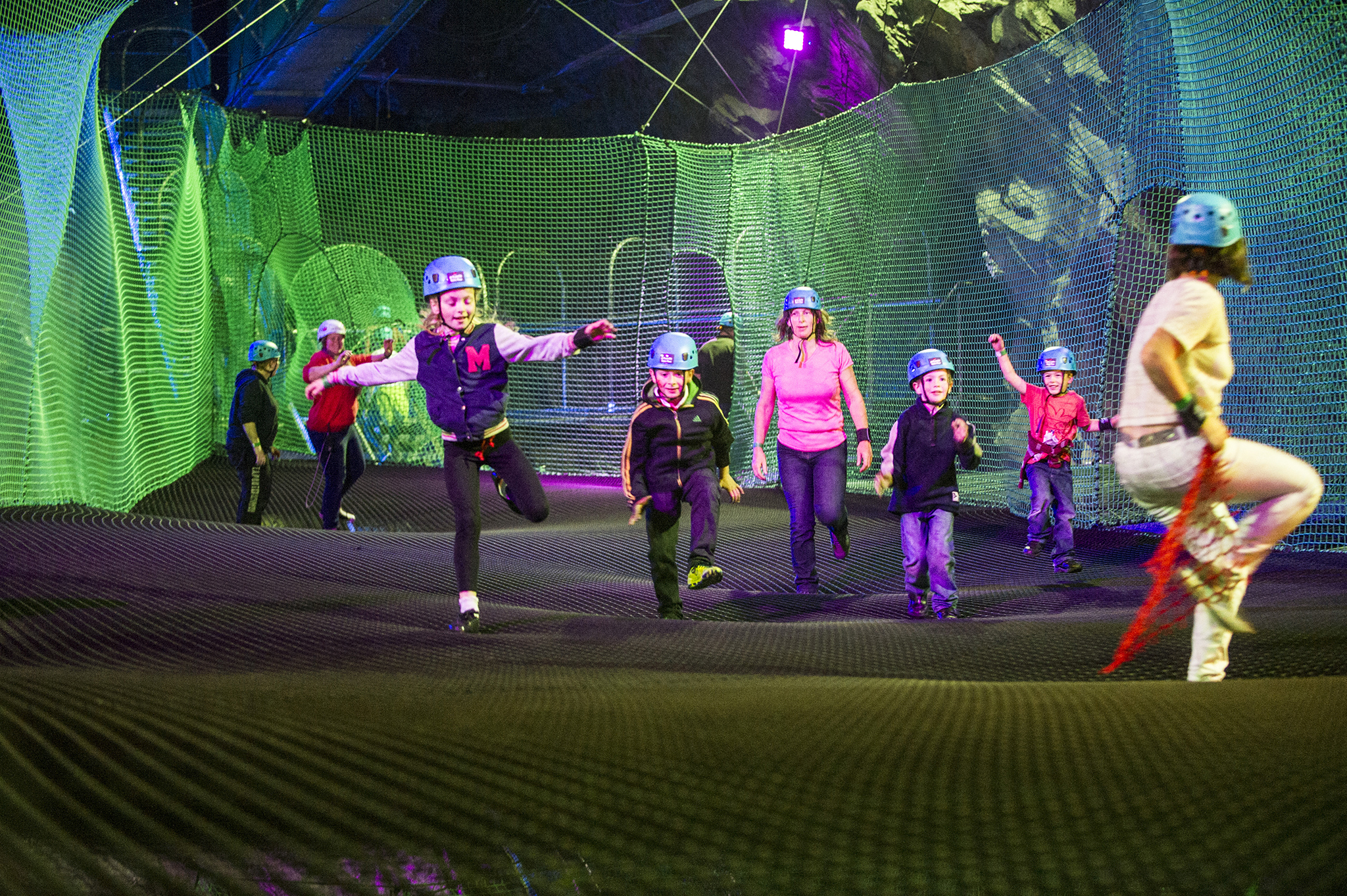 Visitors exploring the illuminated underground nets at Bounce Below